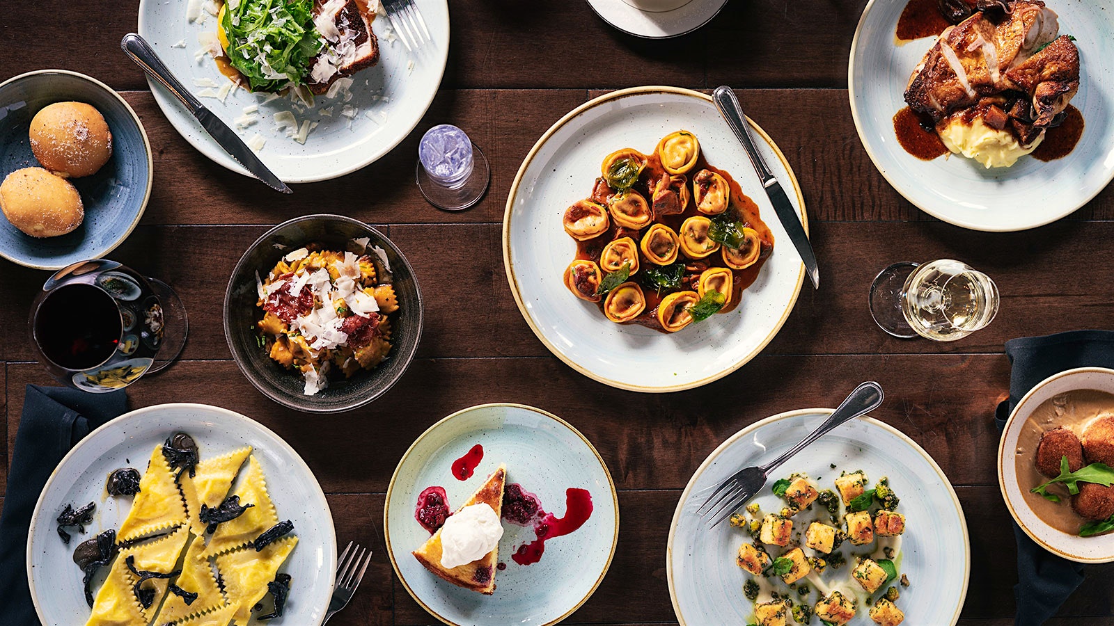 Plates of pastas and glasses of wine at Restaurant Olivia in Denver